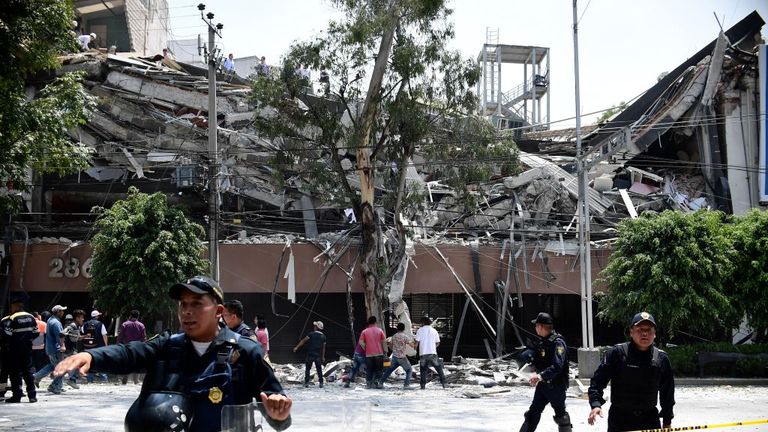 Police try to clear the area around a collapsed building in Mexico City