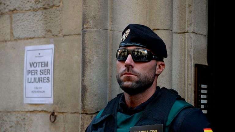 Guardia Civil stands next to a pro-referendum poster reading &#39;Vote to be free&#39; in Catalan
