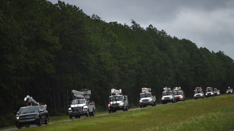 A line of utility trucks drive north on Interstate 75 in Florida