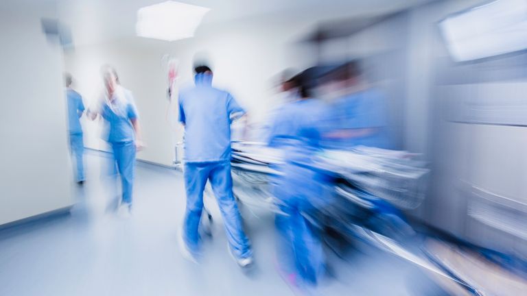 NHS staff push a bed down a hospital corridor