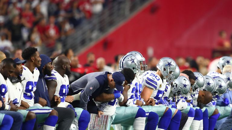 Dallas Cowboys players kneel together with their arms locked prior to the game against the Arizona Cardinals. Mandatory Credit: Mark J. Rebilas-USA TODAY Sports
