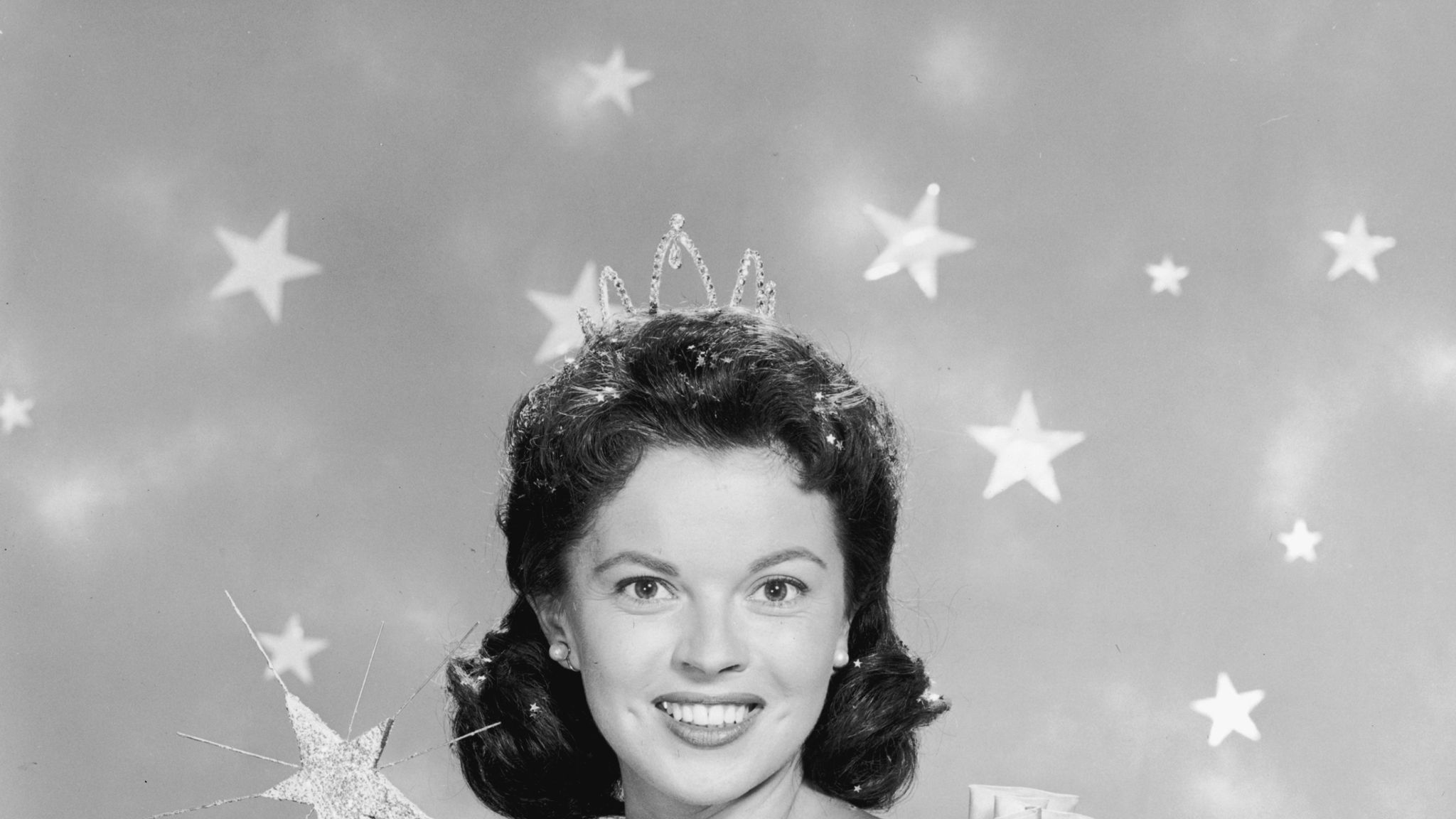 1958: American actor Shirley Temple wears a fairy godmother costume, which includes a magic wand and a tiara, in a promotional portrait for her television series of dramatized fairy tales, 'Shirley Temple's Storybook'. (Photo by Hulton Archive/Getty Images)