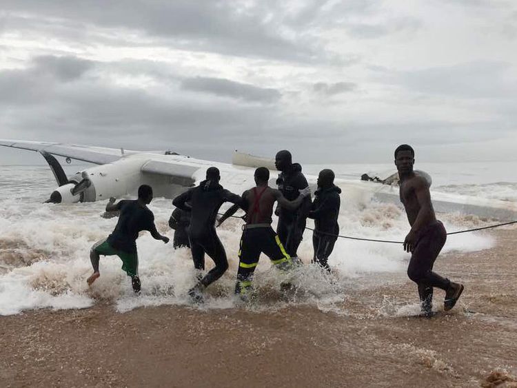 People help with a recovery operation to pull a down plane from the ocean in Ivory Coast