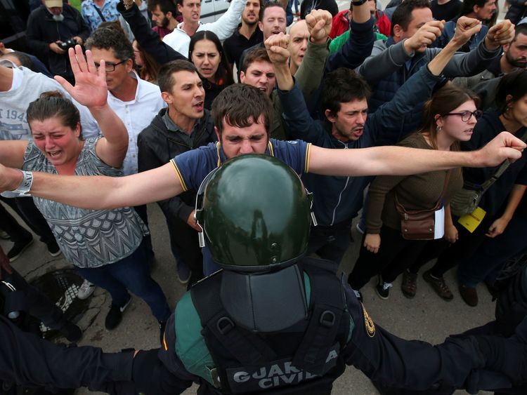 A man faces off with a Spanish Civil Guard officer outside a polling station