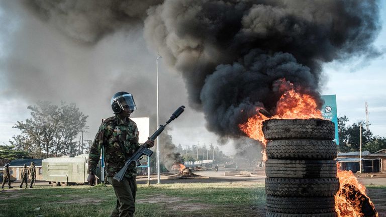 An anti-riot police officer near tyres set alight by opposition supporters in Kisumu