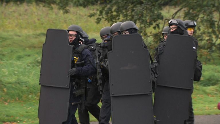 Armed police carry shields as they respond to the mock attack