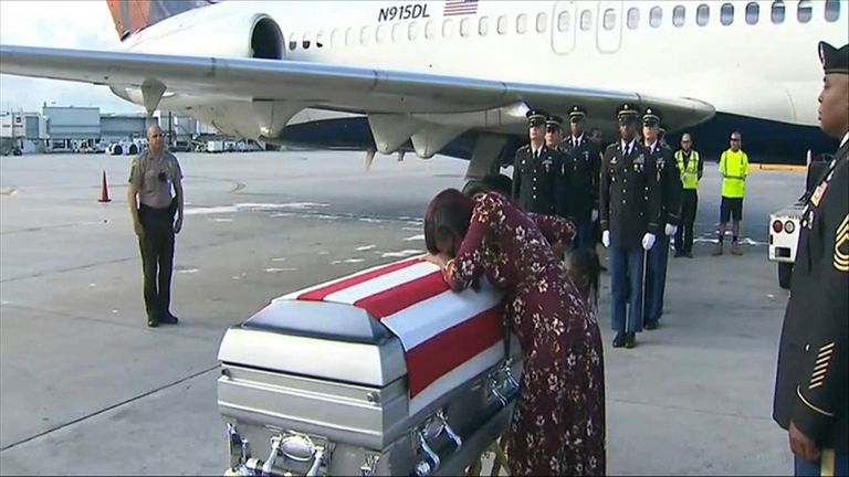 The wife of Sgt La David Johnson weeps on his coffin as his body is returned to Miami