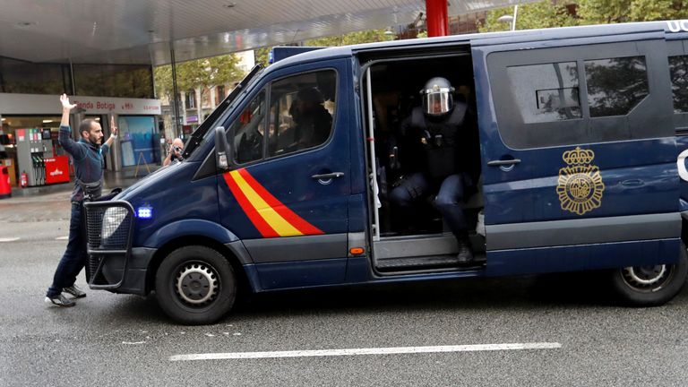 A demonstrator blocks a riot police van near a polling station for the banned independence referendum in Barcelona