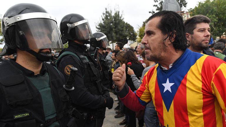 A man dressed in the Catalonian flag confronts officers 