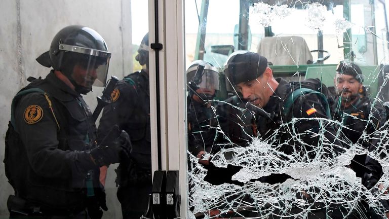 Spanish Guardia Civil guards brake the door of a polling station in Sarria de Ter