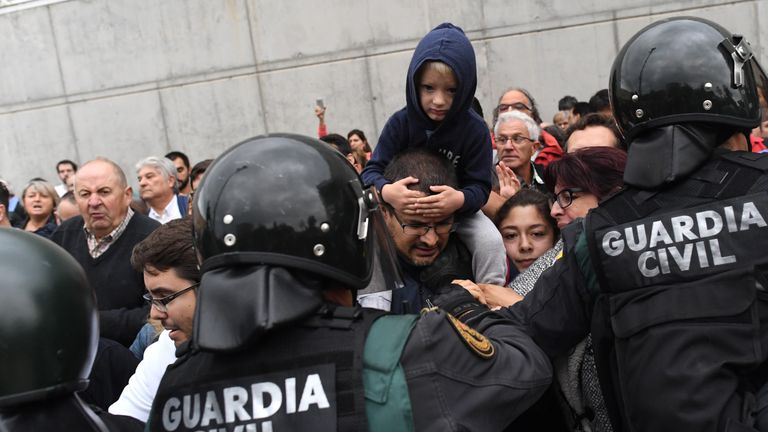 A child sits on the shoulders of a person as police move in on the crowds