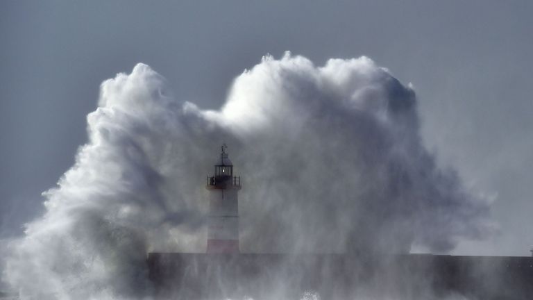 Waves crash over Newhaven Lighthouse in East Sussex