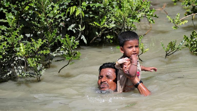 A man holds his child as he swims across the Bangladesh border 