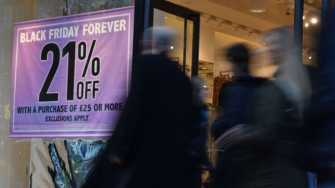 Shoppers pass a promotional sign for Black Friday sales discounts on Oxford Street