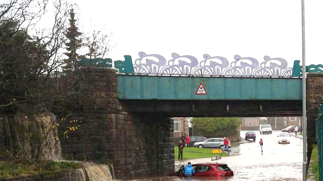 A car is stuck in floodwater underneath a railway bridge in Cumbria