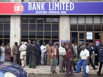 People queue to draw money outside a bank in Harare