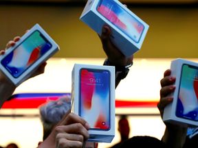 Customers hold up newly purchased iPhone Xs outside the Apple store in Sydney