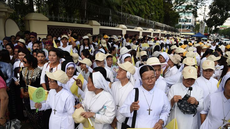 Catholic faithful wait along a street in Yangon