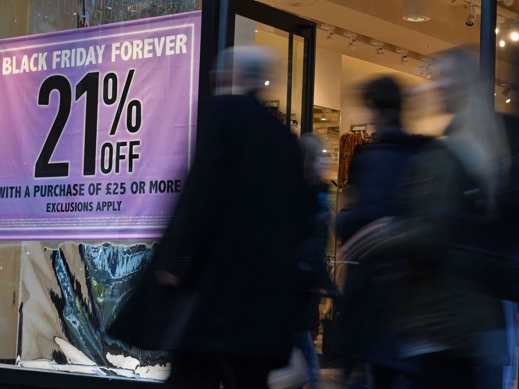 Shoppers pass a promotional sign for Black Friday sales discounts on Oxford Street