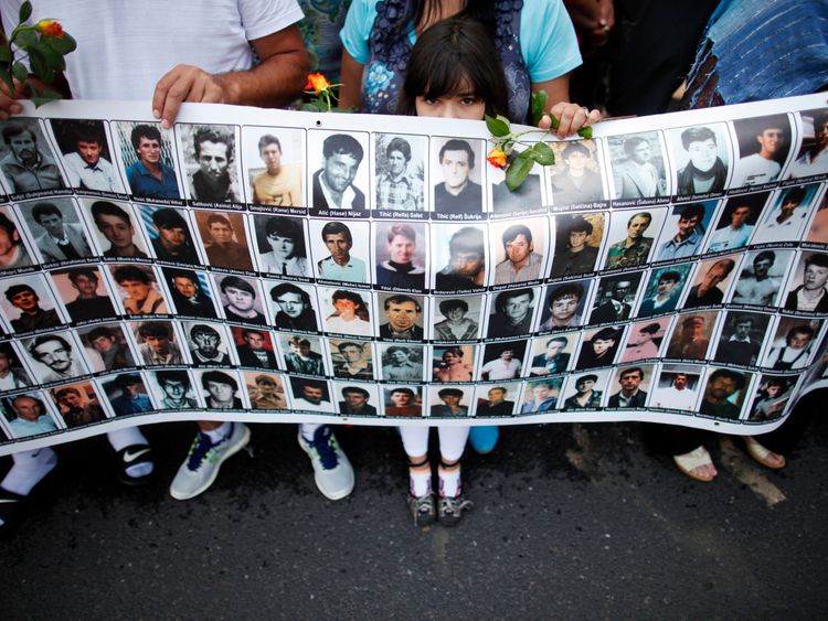 A child holds a poster with portraits of people killed at Srebrenica