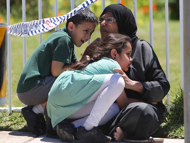 A woman hugs her children near the school