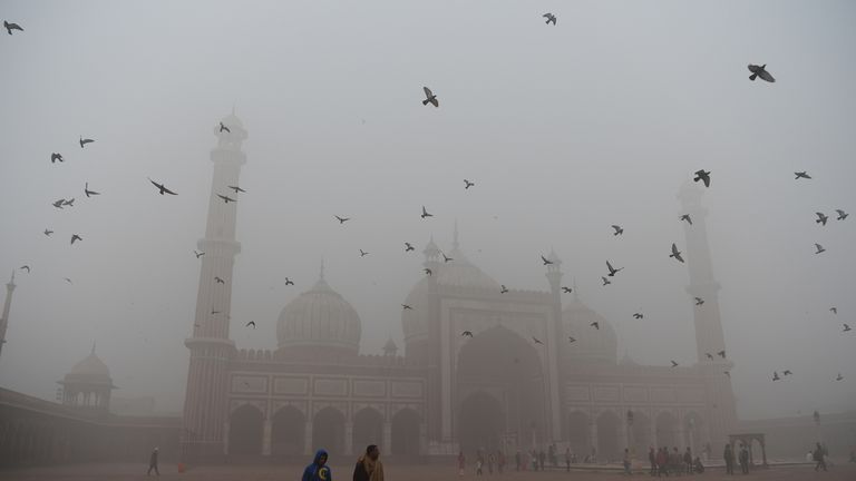 Visitors walk through the courtyard of Delhi&#39;s Jama Masjid in the smog