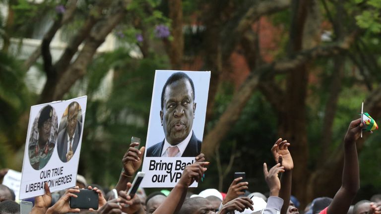 Protesters hold posters showing support for Emmerson Mnangagwa