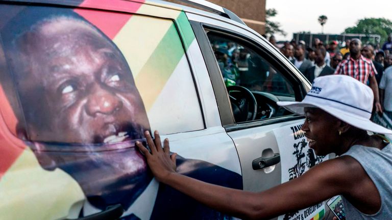A supporter of Emmerson Dambudzo Mnangagwa touches an image of the politician glued on a SUV at the ZANU-PF headquarter in Harare, on November 22, 2017