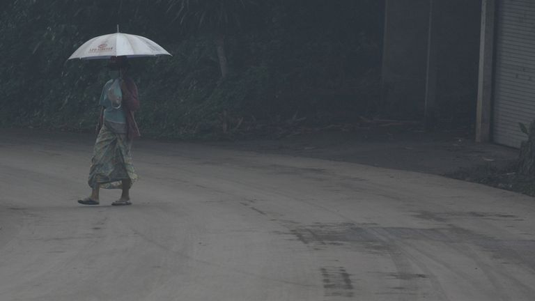 A woman uses an umbrella as she walks through ash from Mount Agung volcano during an eruptiuon in Bebandem Village, Karangasem, Bali