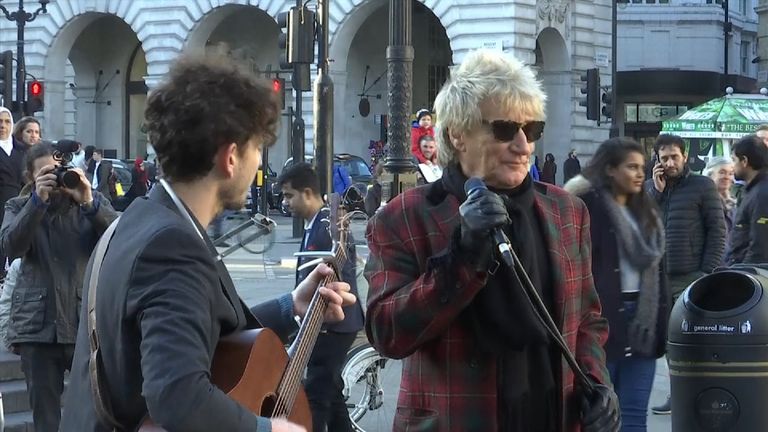 Rod Stewart gives an impromptu performance with a busker in London&#39;s Piccadilly Circus   