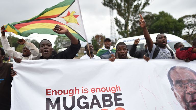 People wave a Zimbabwean national flag and carry banners during a demonstration demanding the resignation of Zimbabwe's president on November 18, 2017 in Harare.