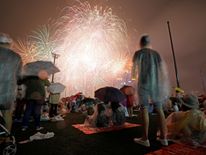 People watch fireworks in the rain ahead of the New Year at Marina Bay in Singapore