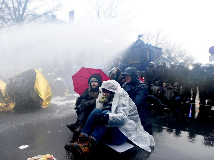 Protesters attempt to withstand the water by using umbrellas