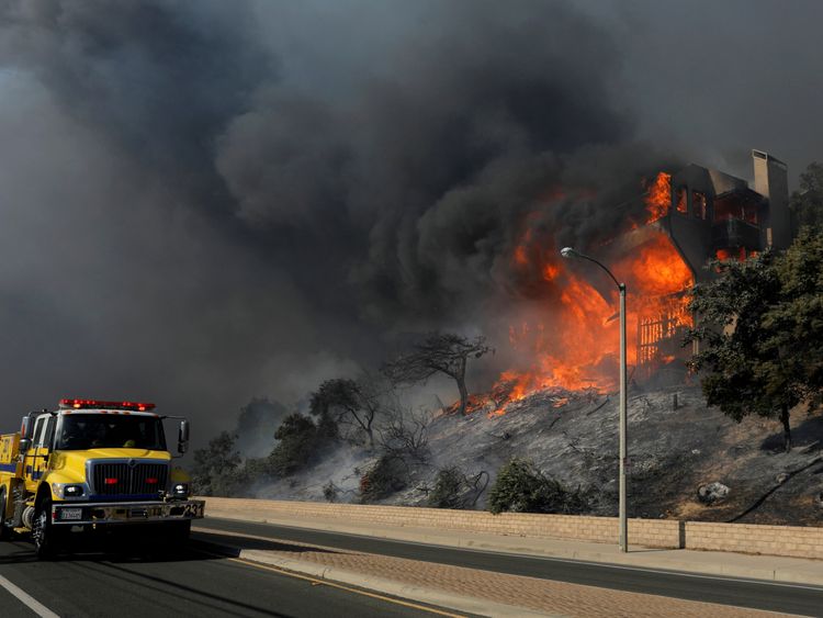 A fire crew passes a burning home during a wind-driven wildfire in Ventura, California