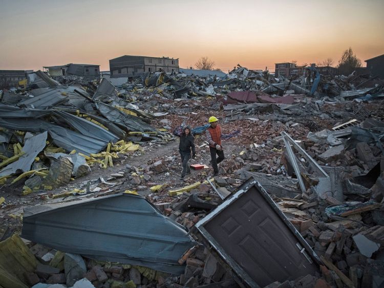 Chinese workers salvage items from buildings demolished by authorities in an area that used to have migrant housing