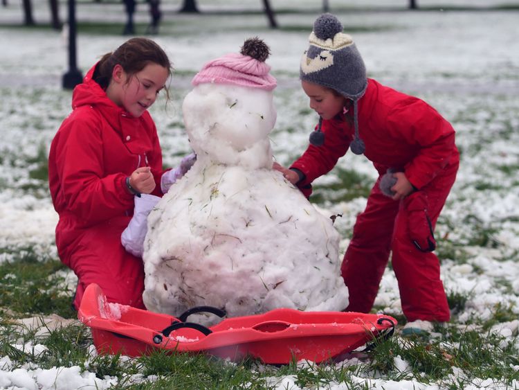 Two girls make a snowman on Primrose Hill in London