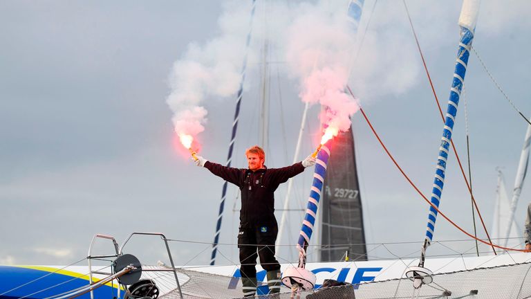 Francois Gabart celebrates aboard his trimaran, Macif, at the end of his epic journey