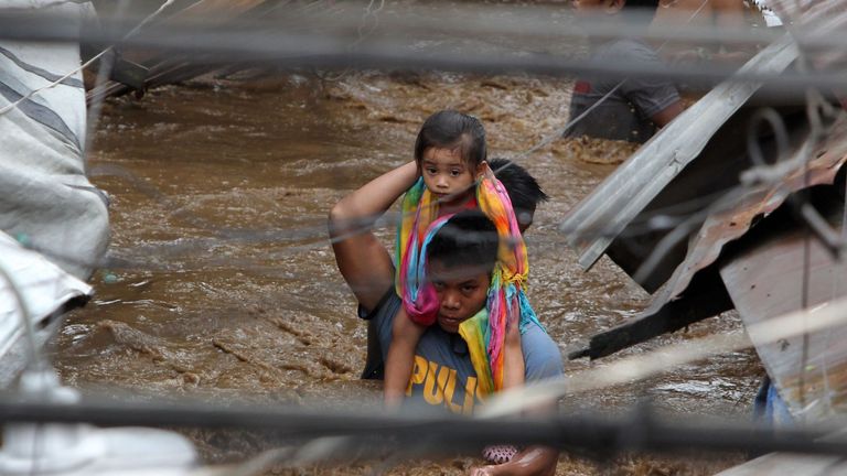 A policeman carries a young girl along a flooded street in Cagayan City