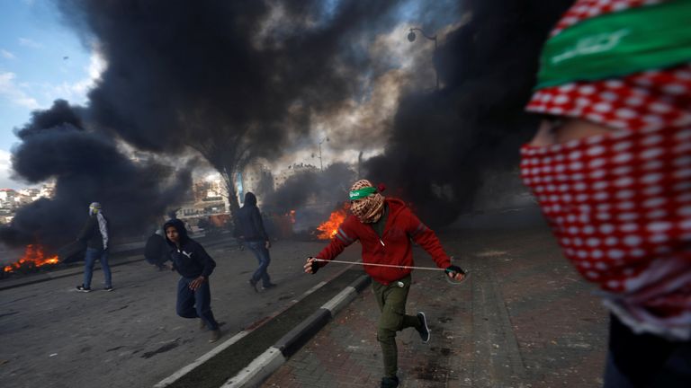 Palestinian protesters run during clashes with Israeli troops