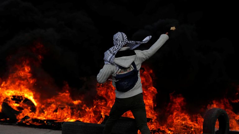 A Palestinian protester hurls stones towards Israeli troops during clashes in Ramallah
