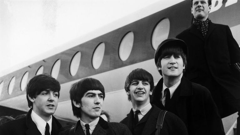 1964:  British pop phenomenon The Beatles standing on the steps of an aeroplane at London Airport