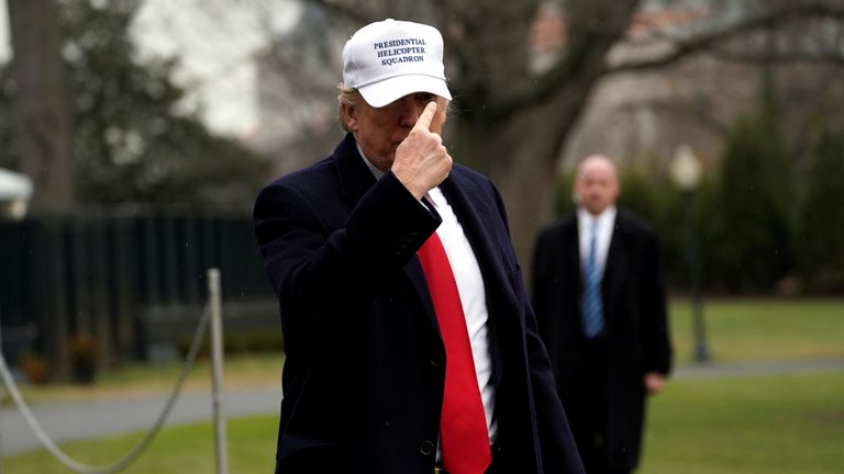 U.S. President Donald Trump points to his hat for the press on South Lawn as he returns to the White House 