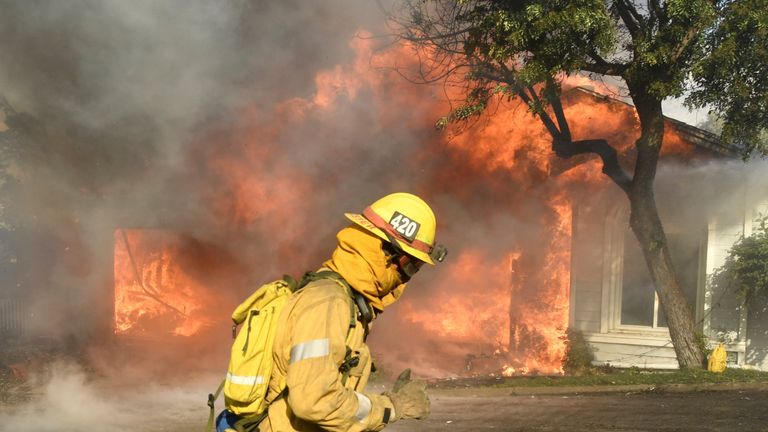 Firefighters battle to save one of many homes burning i