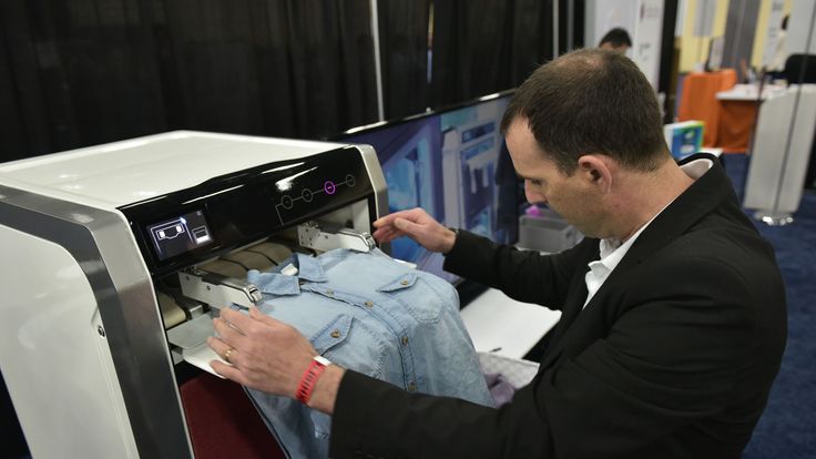 An exhibitor demonstrates the FoldiMate laundry folding machine