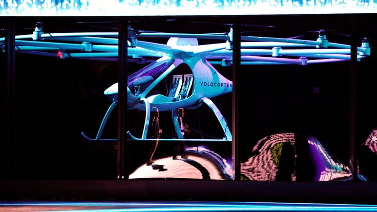 Brian Krzanich, Intel CEO, (R) is reflected in protective glass as atwo-seater Volocopter drone flies on stage at the Intel Keynote address at CES
