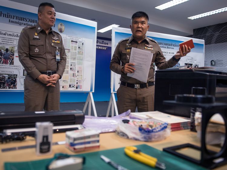 The immigration chief holds up a fake passport during the news conference