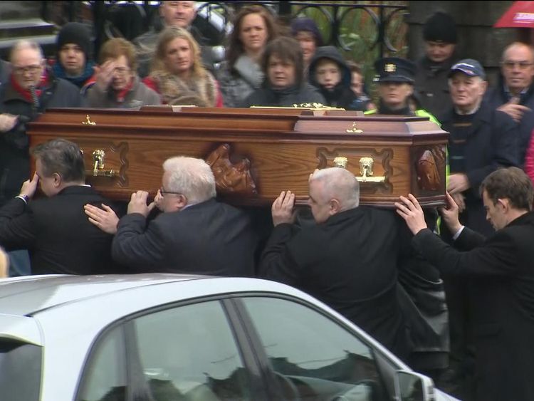 The coffin being carried as mourners watch on