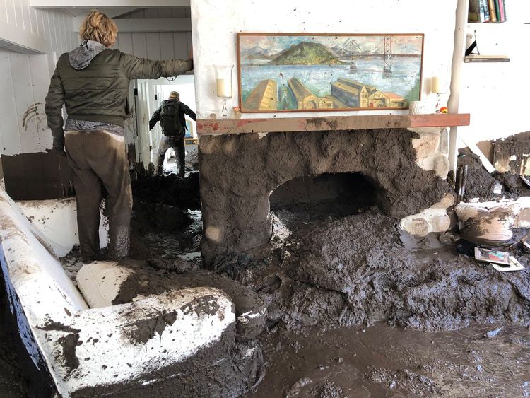 Family members inspect the inside of a home covered in mud