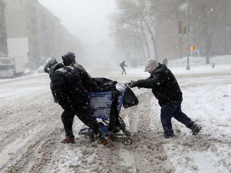 A group of men struggle against the storm as they cross 125th street in upper Manhattan, New York