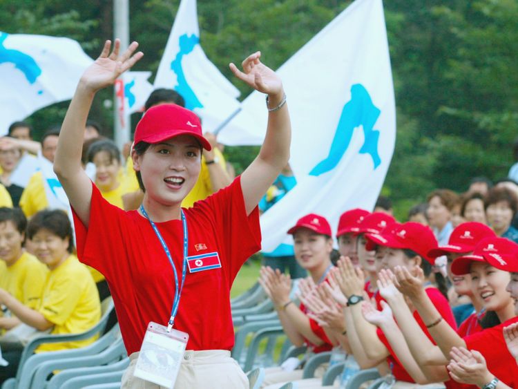 North Koreans (red shirts) cheer as South Koreans (yellow shirts) wave unified Korean peninsula flags in 2003